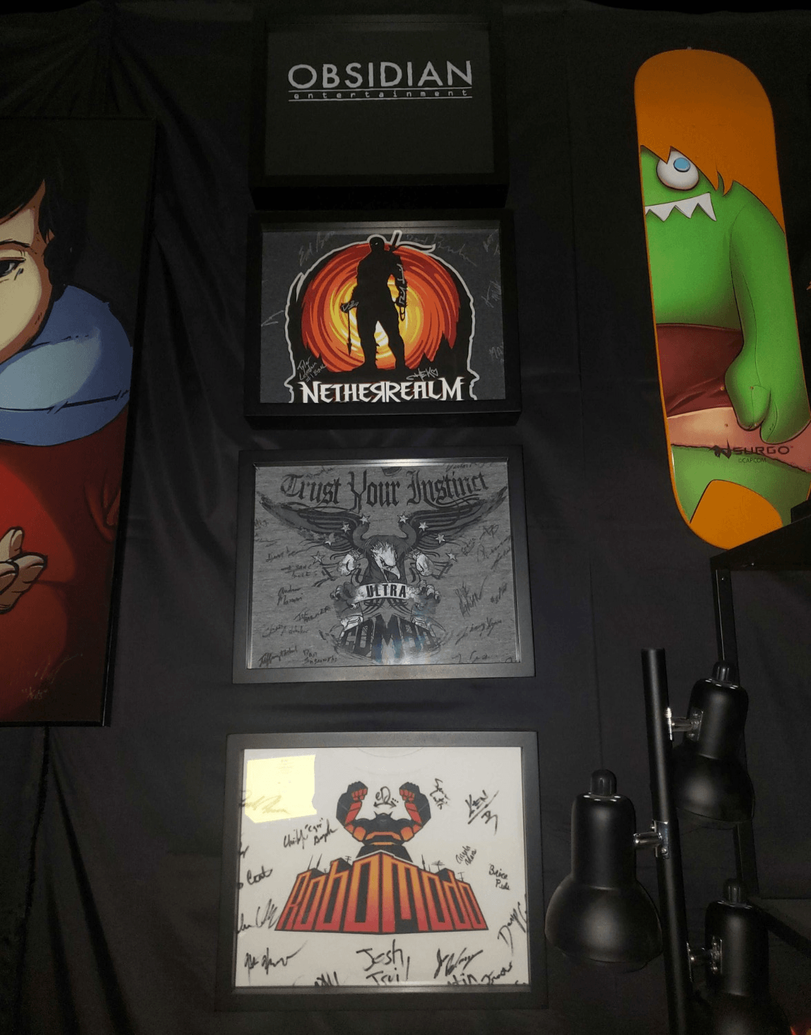 Four gaming tee shirts framed and displayed in Shart® Original T-Shirt Frame 4-Pack.  Tee shirts include Obsidian Entertainment, Netherrealm, Killer Instinct and Robomodo.